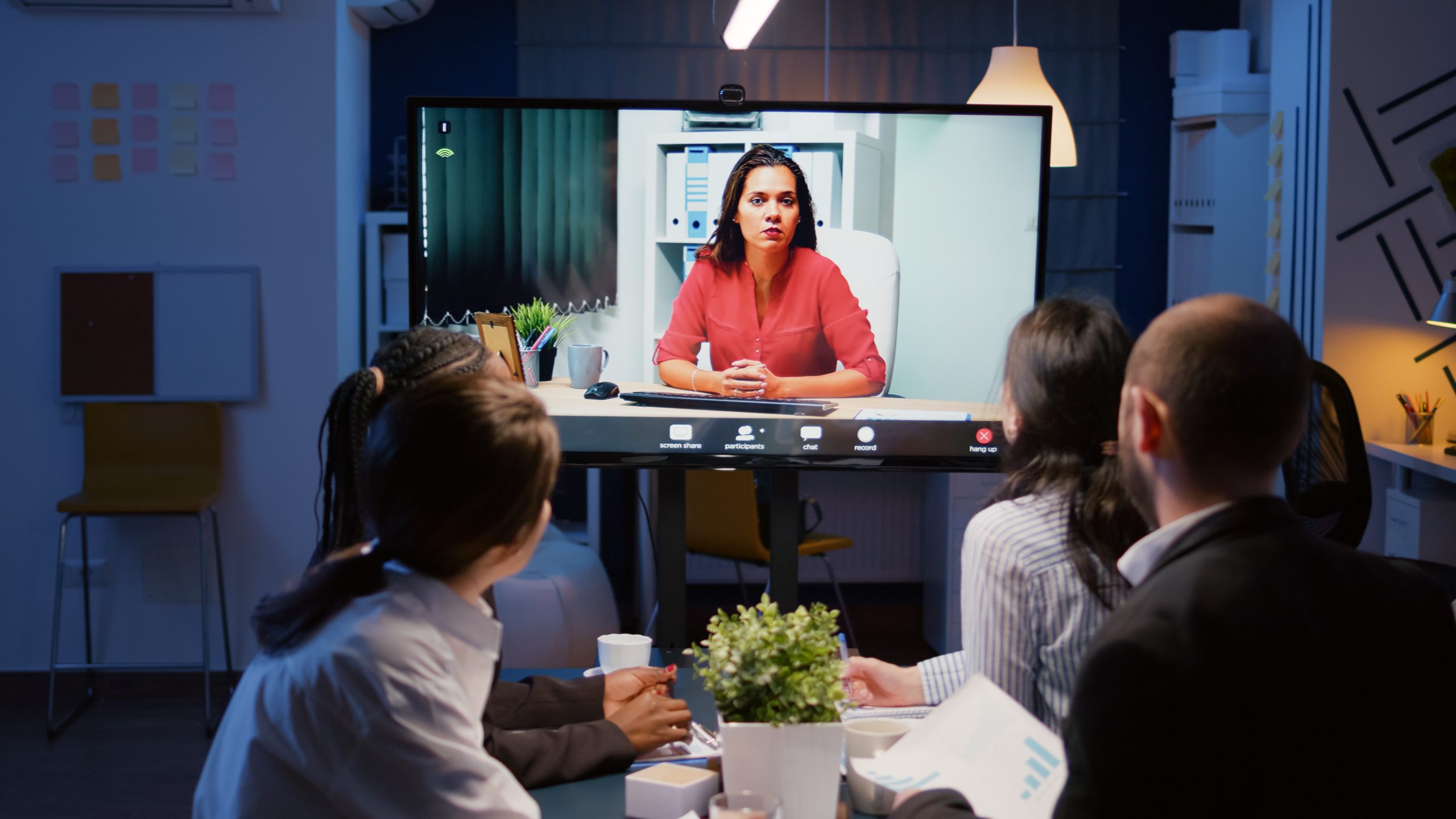 Diverse multi-ethnic businesspeople discussing management strategy during online videocall meeting conference overworking in office room. Remote businesswoman solving company problem late at night